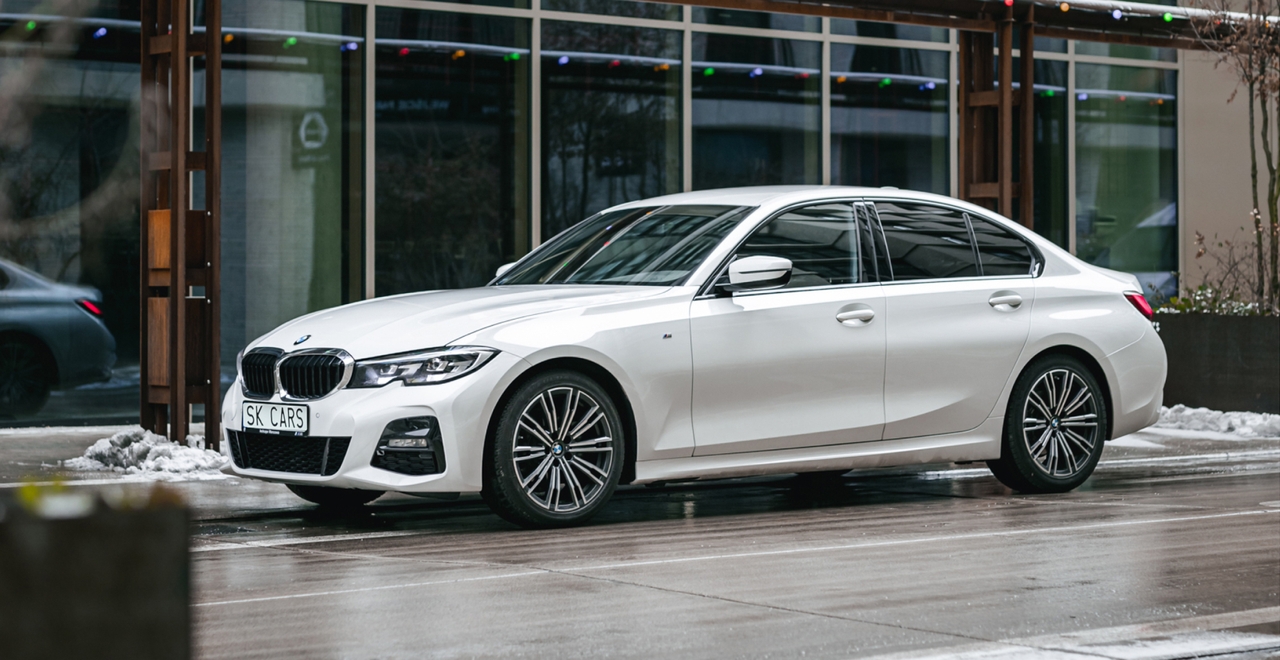Biały BMW 3 Series przed nowoczesnym budynkiem. Elegancki sedan do wynajmu w SK CARS dla wygodnych podróży w mieście i poza nim.