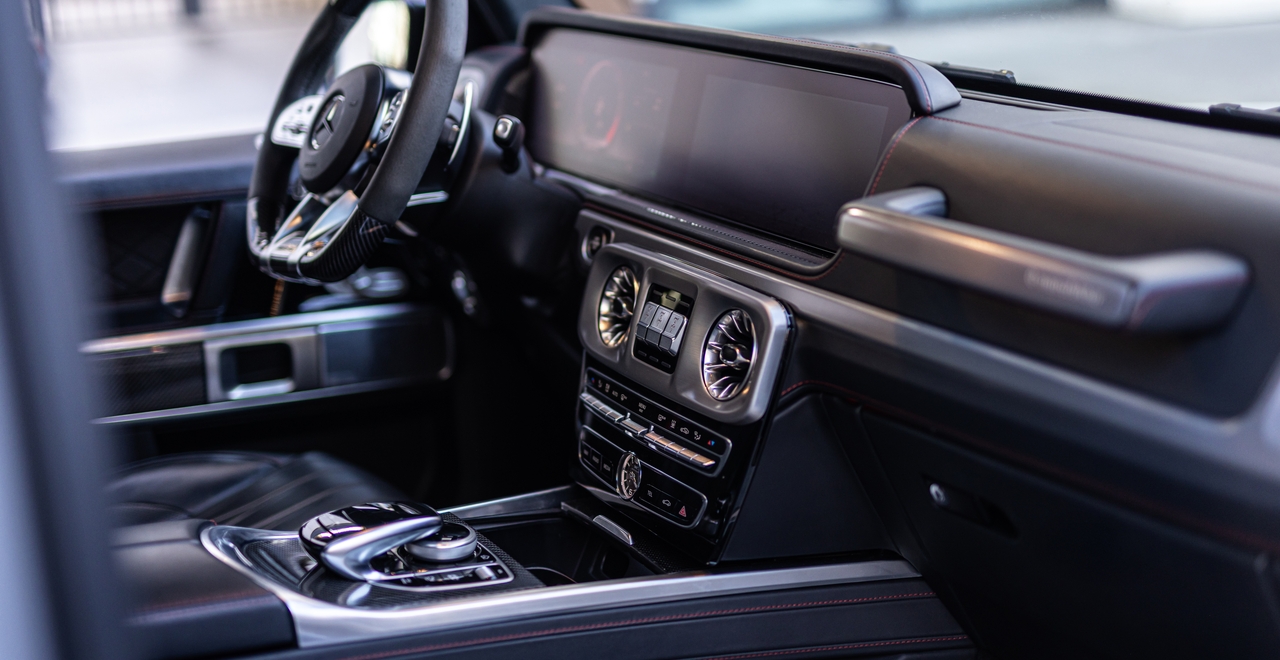 Konsola centralna Mercedes-AMG G63 z podwójnym ekranem, charakterystycznymi nawiewami i przyciskami blokady dyferencjałów — wszystko pod ręką, wszystko pod kontrolą.