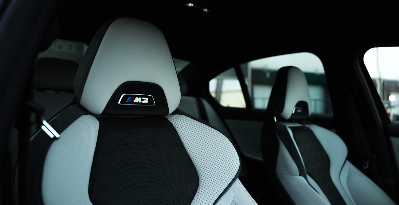 Sportowe fotele przednie BMW M3 Competition z logo M3 i dwukolorową tapicerką.