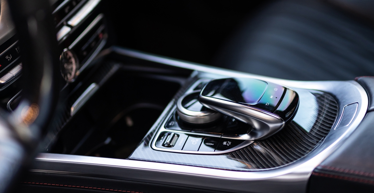 Konsola centralna Mercedes-AMG z wykończeniem z włókna węglowego, panelem dotykowym i przyciskami sterowania multimediami oraz funkcjami pojazdu.