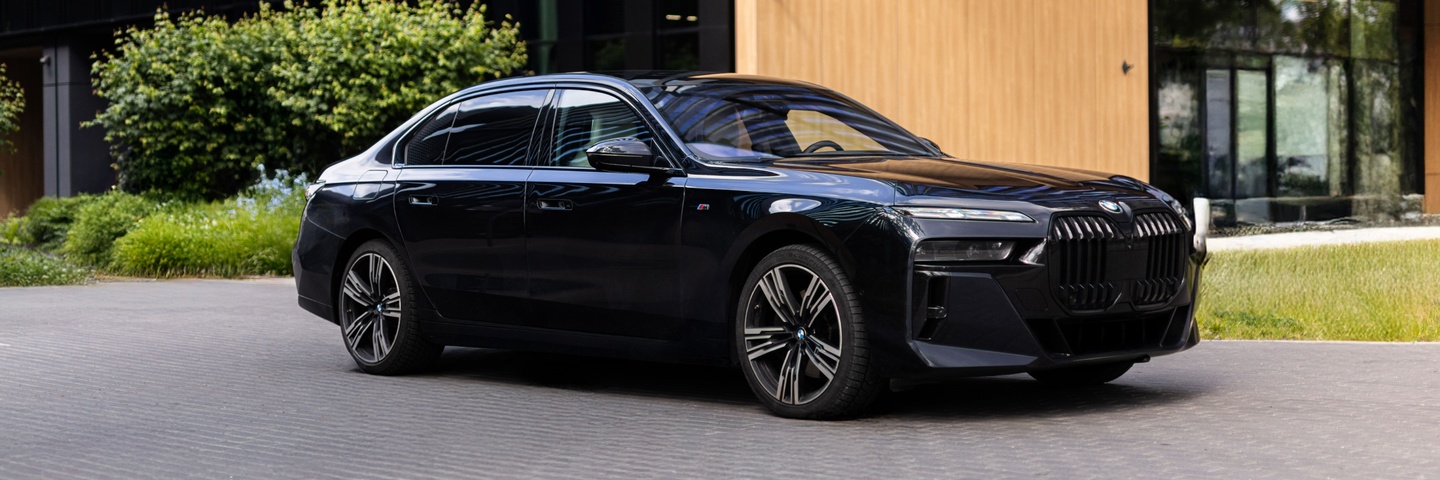 BMW 740d xDrive – премиум-седан нового поколения с M-пакетом, в элегантном чёрном цвете. Фото на фоне современной архитектуры Варшавы. В аренду в SK CARS.