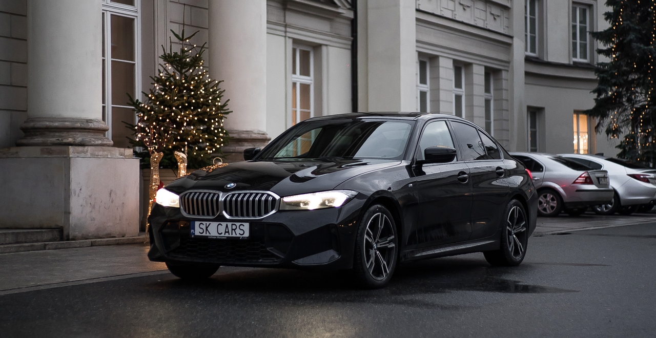 Elegancki BMW Series 3 przed świątecznie ozdobionym hotelem, podkreślający luksus i wygodę wynajmu z SK Cars.