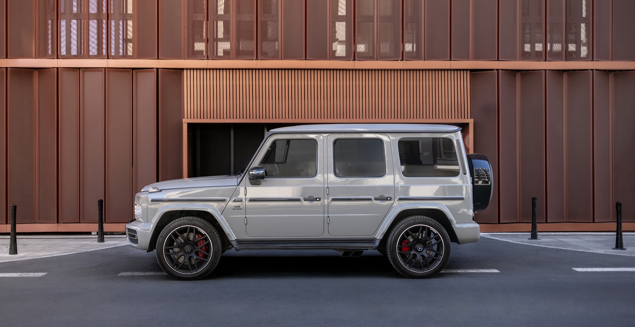 Mercedes-AMG G63 na tle nowoczesnego budynku: potężny SUV z charakterystycznym designem, efektownymi felgami i agresywnym stylem, łączący luksus i terenowe możliwości.