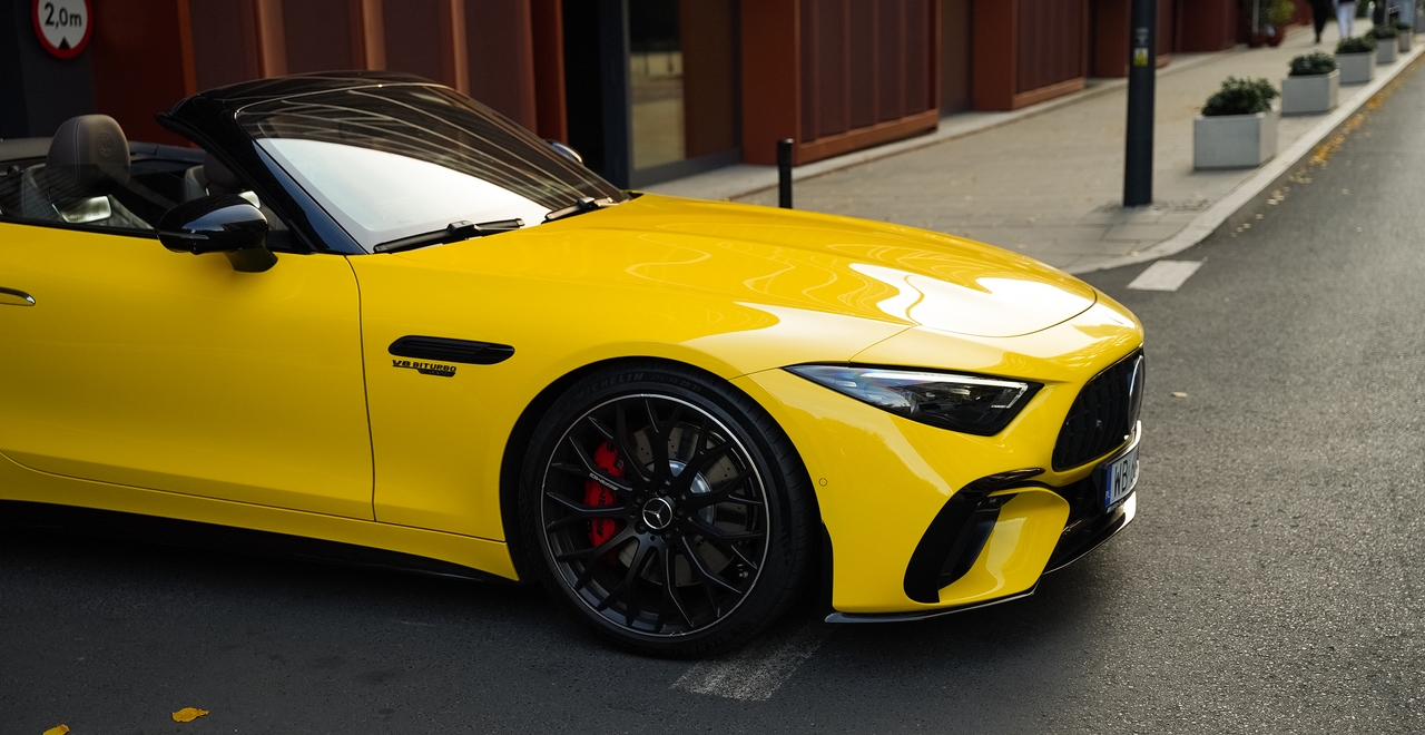 Mercedes SL55 AMG — żółty kabriolet, widok z przodu z boku, czerwone zaciski hamulcowe i emblemat V8 Biturbo