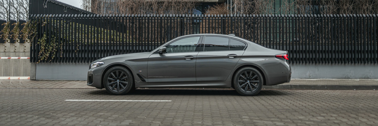 Widok z boku na szary BMW 5 Series, podkreślający elegancję i moc. Zarezerwuj ten samochód w SK CARS, aby doświadczyć wyjątkowej jazdy.